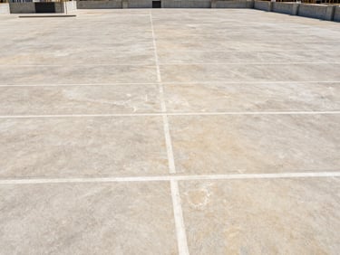 Wide shot of a massive commercial concrete parking lot under construction, clean expansion joints, bright daylight