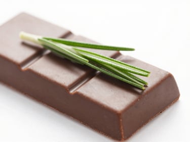 Macro shot of a glossy, perfectly structured chocolate and rosemary entremet slice, clean white background, shallow depth of field.