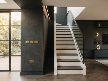 Straight-on architectural shot of a modern, high-end UK residential renovation, warm natural light illuminating crisp plastering lines and flush-mounted electrical fixtures, deep charcoal tones, sharp focus, 35mm.