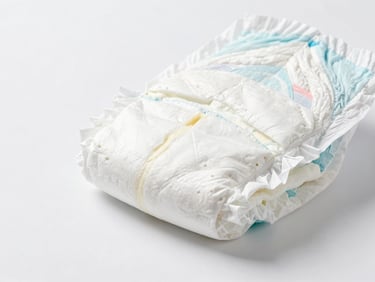 Cross-section of a baby diaper, showing multi-layer construction and absorbent core, sterile white background, macro focus.