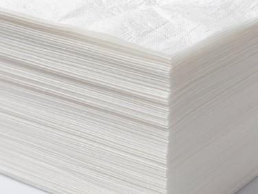 Macro close-up of neatly stacked, white paper tissue with a visible fine texture, sterile studio lighting