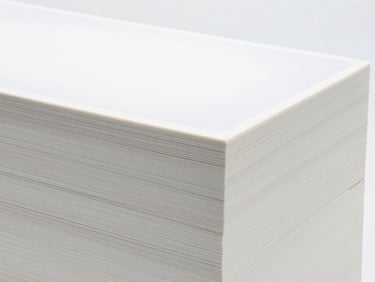 Neatly stacked bulk packaging of specialty paper with a subtle, customizable label area, bright clinical studio light
