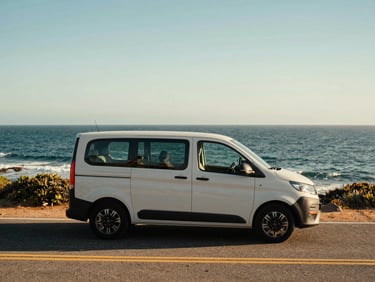 A compact Vanline urban cruiser parked on a scenic coastal road, ocean breeze, bright daylight, agile and adventurous vibe