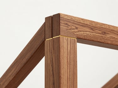 Close-up of a mitered corner of a custom wood frame, showcasing rich grain and precise joinery, bright diffused gallery lighting.