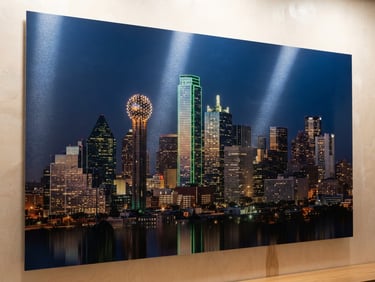 Close-up of a vibrant metal print of a Dallas skyline, catching diffused gallery light, showcasing sharp detail and reflective surface.