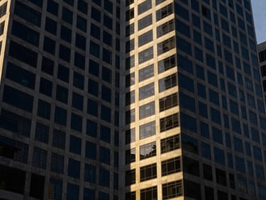 High-contrast architectural angle of modern office towers in Abuja's Central Business District, sharp directional window light, deep navy shadows, 35mm lens.