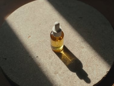 Top-down view of botanical oils on a rough stone plate, warm afternoon light casting long dramatic shadows.