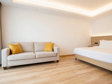 Deluxe suite room interior with elegant seating area, plush king bed, clean wooden flooring, warm lighting