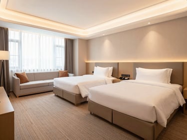 Executive hotel suite, two large beds, separate lounge area with modern sofa, bright warm lighting, elegant finishes, 24mm lens.