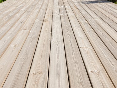 Wide environmental shot of a restored wooden garden decking area, clean natural wood grain visible, bright natural daylight, 35mm lens