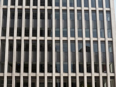 Modern corporate building exterior in a bustling international city, desaturated, high-contrast, bright natural daylight.