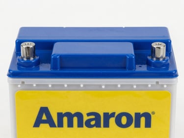 Clean close-up of an Amaron car battery, new and gleaming, crisp workshop lighting, straight-on product shot, blue and yellow tones.