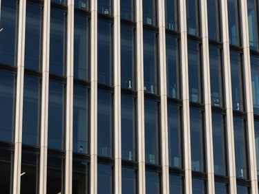 An abstract structural pattern of modern steel and glass building facades reflecting bright natural daylight, 35mm.