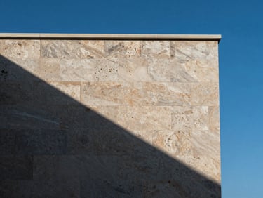 Close-up of premium Brač limestone facade against a clear blue sky, architectural detail, sharp shadows, minimalist composition.