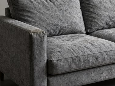 A faded grey fabric minimalist modern sofa with worn armrests and sagging seat, low-key lighting showing the worn texture of the textile.