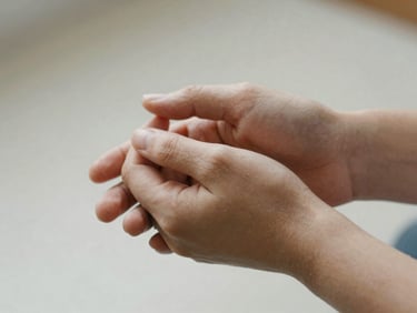 Hands gently holding another person's hands in a gesture of support, close-up, soft diffused natural light, muted compassionate tones, shallow depth of field, 35mm