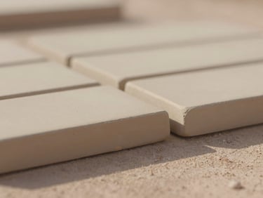 Macro photograph of hand-pressed raw clay tile edges drying in soft Arizona morning light, shallow depth of field, 35mm