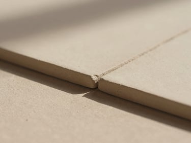 Macro photograph of hand-pressed raw clay tile edges casting gentle shadows in soft directional Arizona sunlight, 35mm warm editorial style