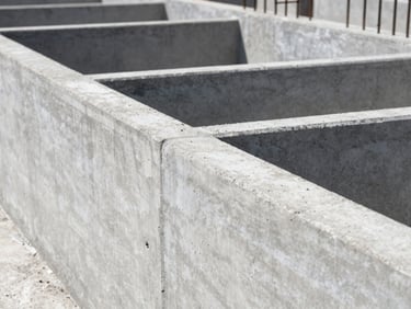 Close-up of newly poured concrete foundation walls, smooth finish, with rebar visible, under bright sunlight, deep depth of field.