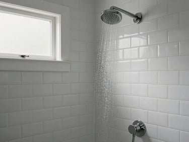 Freshly tiled bathroom shower niche with white subway tile, matte grout lines, and a rainfall showerhead, lit by soft natural light from a frosted window