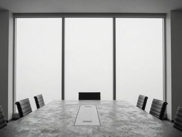 An empty, quiet executive boardroom with a concrete conference table, floor-to-ceiling windows, diffused north-facing daylight