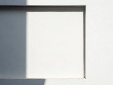Abstract geometric shadow-play on a pristine white wall, sharp lines, minimalist architectural framing, high contrast, 35mm