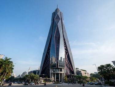Low-angle heroic architectural perspective of a modern steel and glass skyscraper in Kuala Lumpur under crisp morning daylight, sharp focus, medium format.