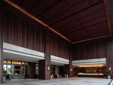 Wide-angle environmental shot of a luxury hotel lobby interior with high ceilings, dark wood paneling, and dramatic architectural lighting, sharp focus