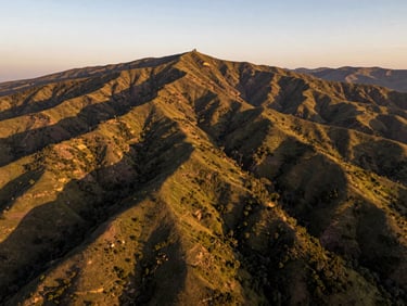 Sweeping golden-hour drone shot of a vast ecological plot in Calca, dramatic mountain shadows, lush green and earth tones
