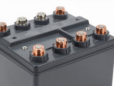 Close-up of large, heavy-duty industrial battery bank with thick copper terminals, clean bright daylight, high-contrast technical details, deep grays and amber accents, 50mm lens