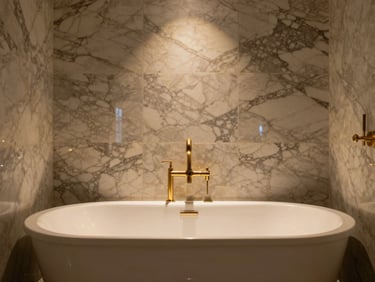A lavish master bathroom sanctuary, polished bookmatched Calacatta marble walls, brushed gold fixtures, deep freestanding tub under soft warm glow