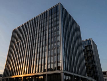 Architectural detail of a modern high-end corporate headquarters, clean steel and glass facade, dramatic twilight golden-hour light, deep navy tones, wide-angle lens
