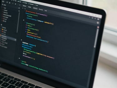 Close-up overhead of a code editor screen showing structured component architecture, clean indentation visible under cool daylight from a nearby window, keyboard partially in frame