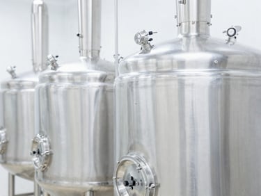 Close-up of clean, polished stainless steel bioreactor tanks in a high-tech food processing plant, bright white studio lighting, sharp focus, 35mm