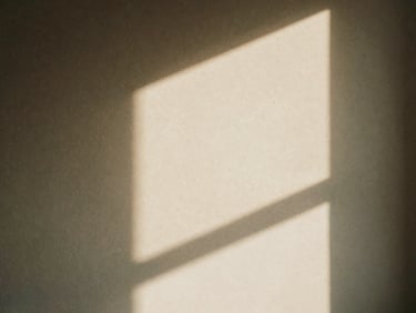 Abstract light pattern on a textured wall, created by soft, indirect window light, warm shadows, and muted earth tones, shallow depth of field.