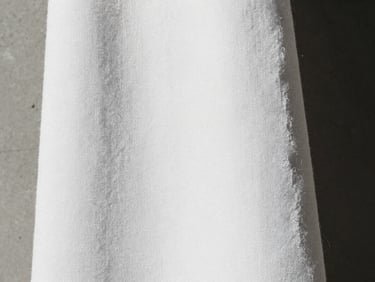 Macro close-up of thick, heavy-weave white Japanese cotton fabric, harsh natural light casting deep shadows in the texture, minimal architectural framing, 35mm