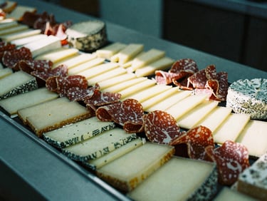 A beautifully arranged cheese and charcuterie display in a modern market, soft shadows, muted green tones, 35mm film.