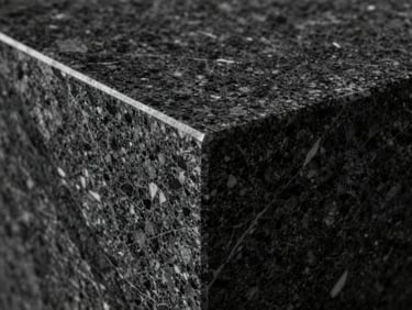 Macro close-up of a flawless mitered joint of a dark quartzite countertop, showcasing sharp 45-degree angles, continuous vein matching, and high-contrast directional lighting.