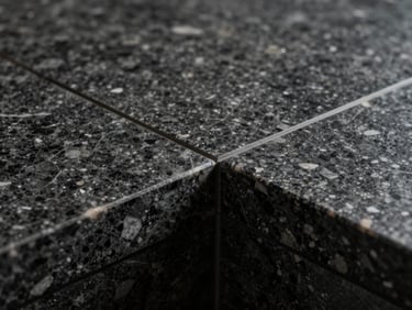 Extreme close-up of a flawless mitered joint on a dark quartzite countertop, showcasing invisible seams, sharp architectural lines, dramatic studio lighting
