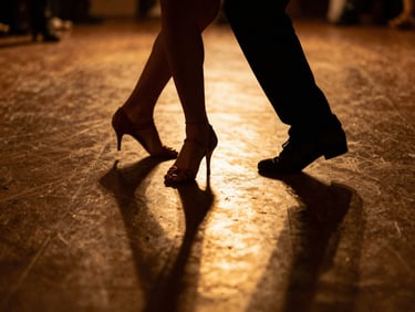 Close-up of a dancer's feet in motion, bathed in golden light, intricate Kizomba steps on a polished dark floor, shallow depth of field.
