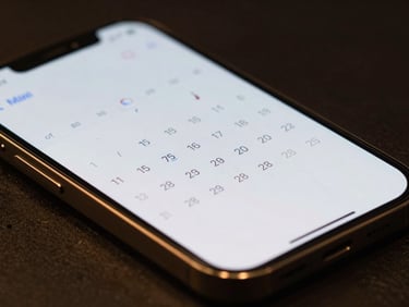 Close-up of a dark titanium smartphone displaying a sleek calendar interface with gold accents, dramatic low-key lighting, razor-sharp focus
