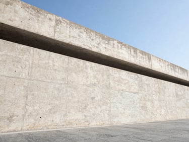 Low-angle architectural photograph of a heavy concrete retaining wall, integrated drainage visible, crisp textures, bright direct sunlight.