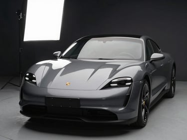 Studio-lit front angle of a charcoal grey Porsche Taycan Turbo S, soft-box highlight on the hood, dark background.