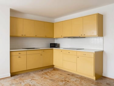 Outdated dark kitchen with old yellow cabinets, worn linoleum flooring, dim lighting, straight-on architectural angle.