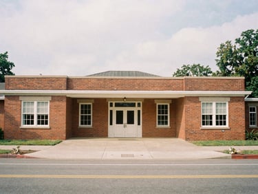 Wide environmental shot of a beautifully restored brick community center, soft overcast daylight, documentary film style.
