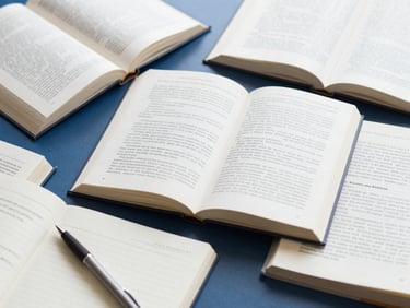 A flat-lay of open academic books, a clean notebook with a pen, soft morning light, workspace of a researcher.