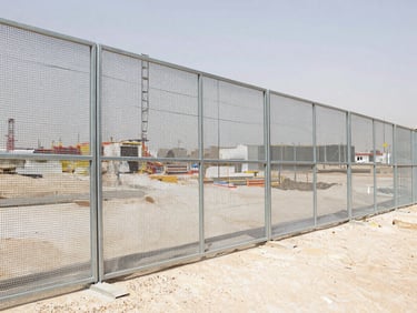 industrial construction site in Riyadh with heavy-duty temporary steel fencing, steel mesh panels, bright daylight, realistic construction photography, 35mm