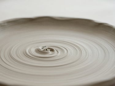 A macro close-up of textured, unfired clay showing subtle fingerprints and tool marks, soft overcast daylight, muted taupe and off-white tones, shallow depth of field, 35mm
