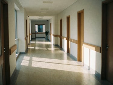 A quiet, sunlit hallway of an established medical center, shadows casting across polished floors, natural morning light, 35mm film