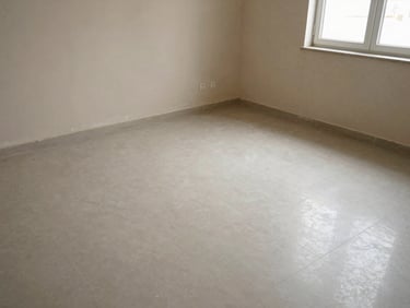 Wide-angle shot of an empty Kuwaiti living room after treatment — baseboards and corners showing fine chemical residue traces, natural window light, tiled floor, no people, documentary overhead angle